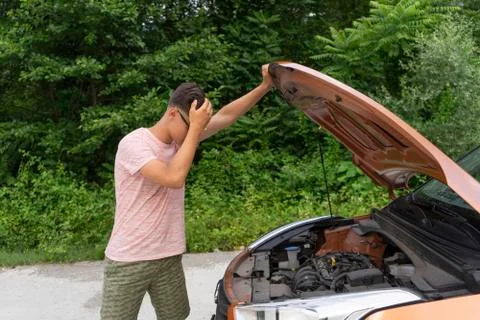 Car problems. Novice driver opens the hood, looking inside. Car-care concept Stock Photos