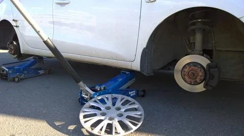 Car raised on jack. Changing flat tire on your own. Wheel replacement. Stock Photos