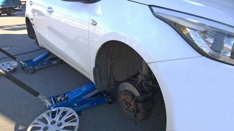 Car raised on jack. Changing flat tire on your own. Wheel replacement. Stock Photos
