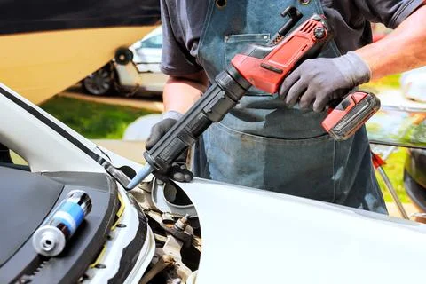 Car repair work is done by worker using power tool in an automotive workshop Stock Photos