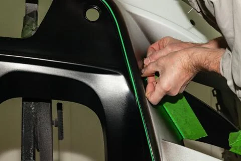 A car repair worker during work pastes with an  green adhesive tape a part of Stock Photos
