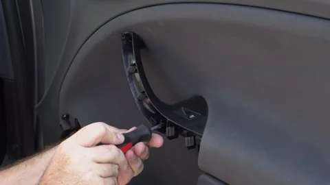 A car repairman disassembles the front door handle with a screwdriver Stock Footage 279024738