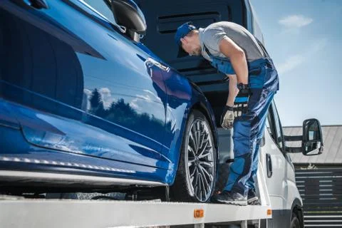 Car Repossession Worker Securing Vehicle on His Towing Truck Foto stock