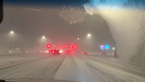 Car ride in the snow in the city  intersection and stops at traffic light 動画素材 326339726