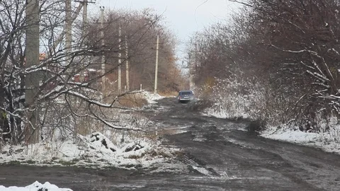 The car rides on a dirty bumpy road. Muddy road along the snow-covered fields Video stock 102302200