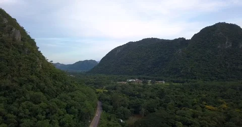 Car on a road between mountains covered with forest under blue cloudy sky Stock Footage 108469685