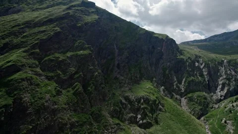 A car road on a hillside in a valley of high mountains. A vacation trip throu Video stock 188315376