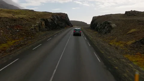 Car On A Road Passing In Between Rocky And Grassy Terrains Stock Footage 231255309