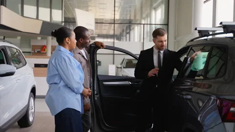 Car salesman showing features of new car to african american couple Stock Footage 310333353