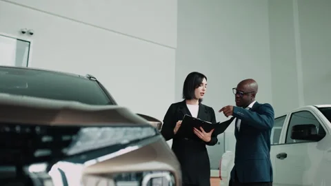 A car salesperson talks with a client and helps them choose Stock Footage 320088094