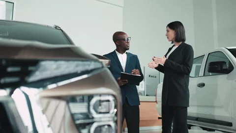 A car salesperson talks with a client and helps them choose the right vehicle Stock Footage 320088095
