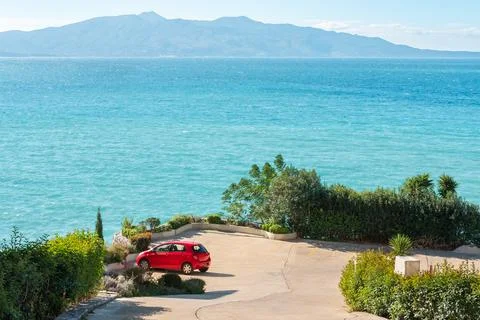 Car on a sea coast. Red car on the road near the ocean on sunny summer day. R Stock Photos