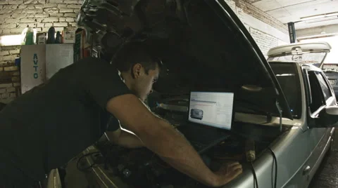 Car service, computer diagnostics: mechanic repairs the damage using the pc in Vídeos de archivo 64859915