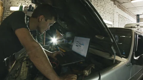 Car service, computer diagnostics: mechanic repairs the damage using the pc in Vídeos de archivo 64860000
