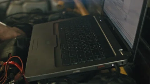 Car service, computer diagnostics: mechanic repairs the damage using the pc in Vídeos de archivo 64860032