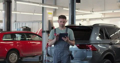 Car service manager uses a tablet computer with an diagnostics software. Stock Photos