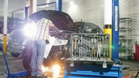 Car service. Mechanic man standing by the car with open hood and checking the Stock Footage 101692564