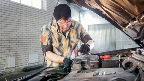 Car service. Mechanic man unplugging a part of the car under the hood Stock Footage 101701554
