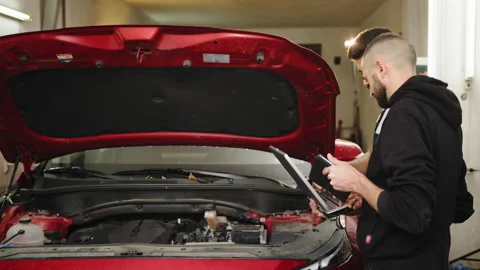 Car service station. Two young bearded attractive mechanics men standing and Stock Footage 233724813