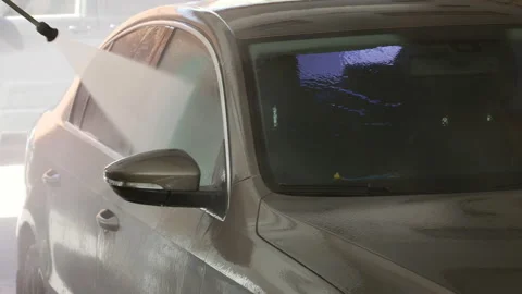 Car service worker in a garage washes a car with water from a hose Stock Footage 106566325