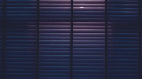 Car shining headlights through window while driving past with blinds closed at n Stock Footage 168987004