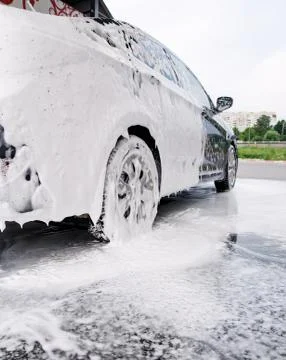 Car on the side in the foam and bubbles from the detergent in the car wash Stock Photos