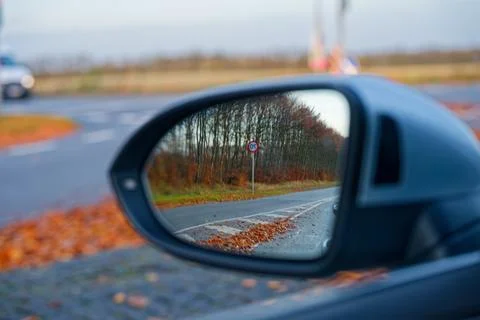Car side mirror reflecting 70 km h speed limit sign in roadside view. Stock-Fotos