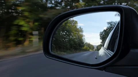 Car side mirror reflecting the countryside road during travel Stock Footage 345638159