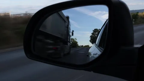 Car side mirror reflecting road and truck Stock Footage 345638160