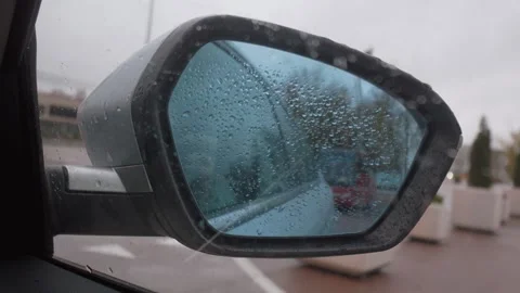 Car side mirror reflecting traffic on rainy day Stock Footage 326148408