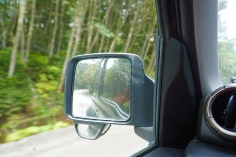 Car side mirror view on forest road. Stock Photos