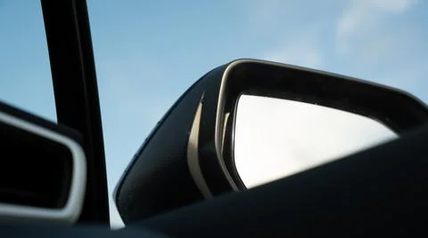 Car side mirror viewed from inside the vehicle against a bright sky, concept of Stock Photos