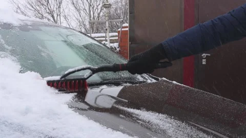 Car in a snowdrift close-up. a man in a dark jacket brushes Stock Footage 173093431