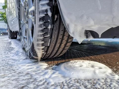 Car soaking under soap foam at self-serve car wash. Stock Photos