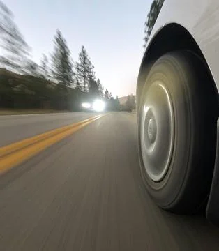 A car is speeding down a road with a bright light shining on the tire Stock Photos