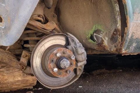 A car stands on the ground missing one wheel, revealing the brake disc. It .. Stock Photos