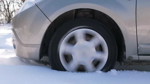 A car struggles to move as its wheel spins in deep snow. The vehicle is Stock Footage 303511659