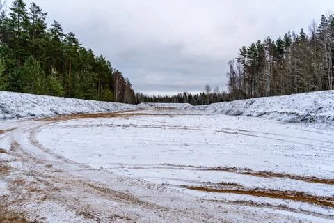 Car Tire Marks on an Empty Field Covered With Snow, Wood in the Background - Stockfoto's