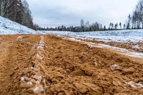 Car Tire Marks on an Empty Field Covered With Snow, Wood in the Background Photos