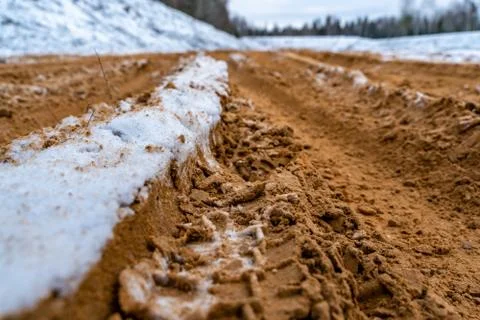 Car Tire Marks on an Empty Field Covered With Snow, Wood in the Background 写真素材