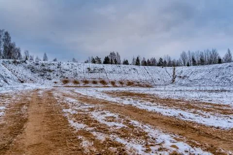 Car Tire Marks on an Empty Field Covered With Snow, Wood in the Background Foto stock