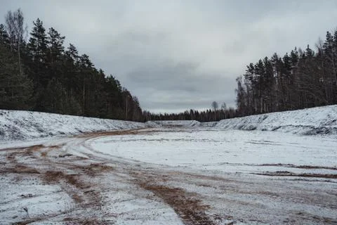 Car Tire Marks on an Empty Field Covered With Snow, Wood in the Background Photos