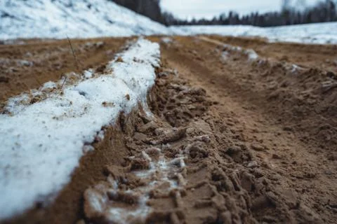 Car Tire Marks on an Empty Field Covered With Snow, Wood in the Background Photos