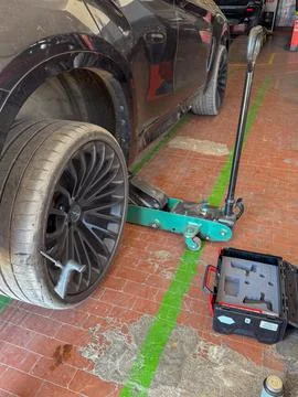 Car Tire Replacement Process with Jack Lift in Garage Fotos de archivo