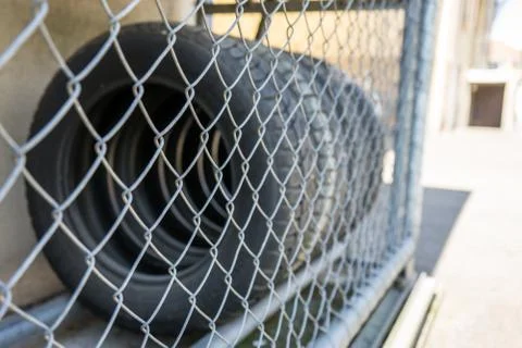 Car tire stack seen through fence Stock Photos
