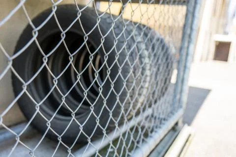 Car tire stack seen through fence Stock Photos