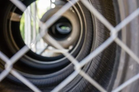 Car tire stack seen through fence Stock Photos