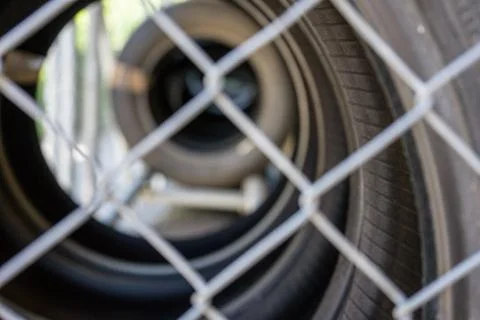 Car tire stack seen through fence Stock Photos