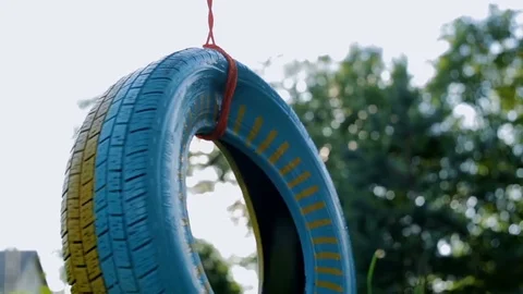 Car tire used as swing on tree. Michelin wheel tied with a rope Stock Footage 78182447