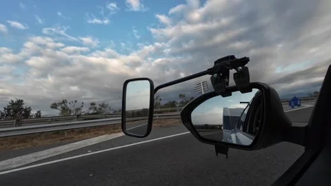 Car towing a caravan on the highway reflected in side mirror Stock Footage 344135797